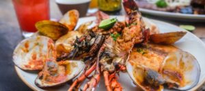 A plate of cooked lobster and clams at a restaurant outside.