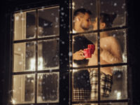 couple looking out of window at snow