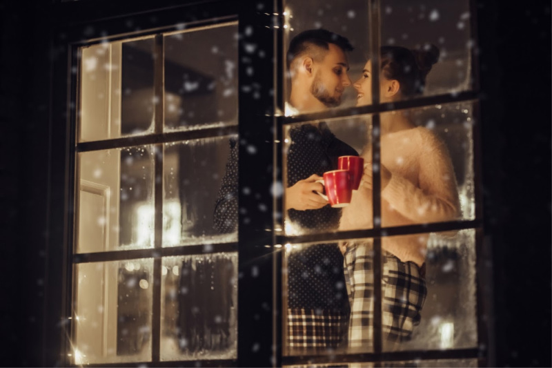 couple looking out of window at snow