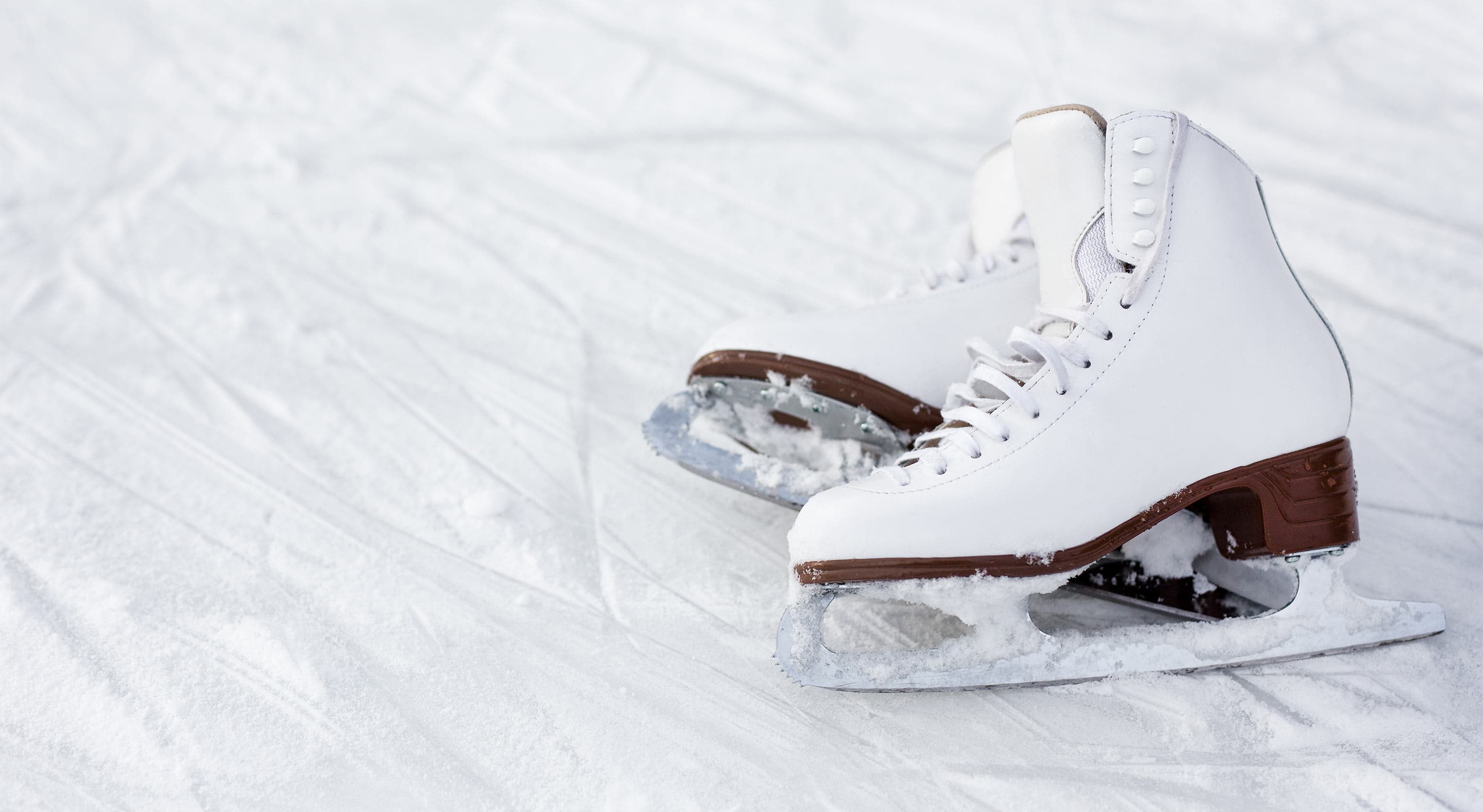 Pair of white ice skates lying in the snow