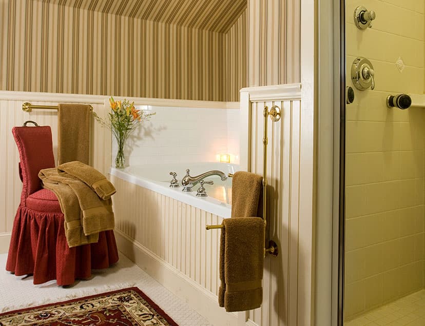 Bathtub with soft furnishings, chair, and towels next to shower