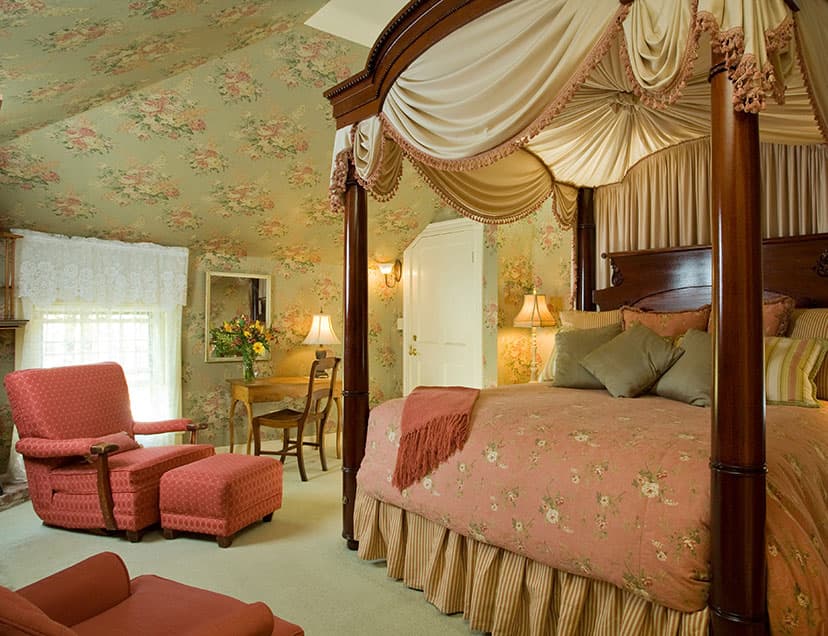 Tall, luxurious Four-poster bed by comfortable sitting area in Room 12