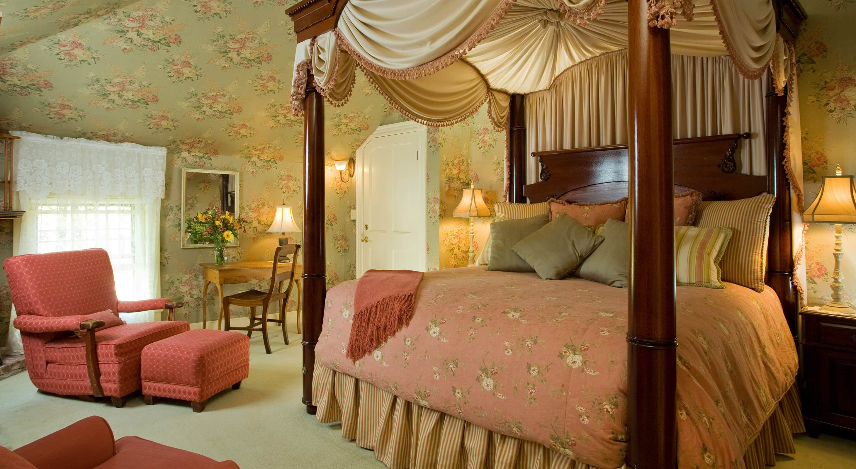 Tall, luxurious Four-poster bed by comfortable sitting area in Room 12