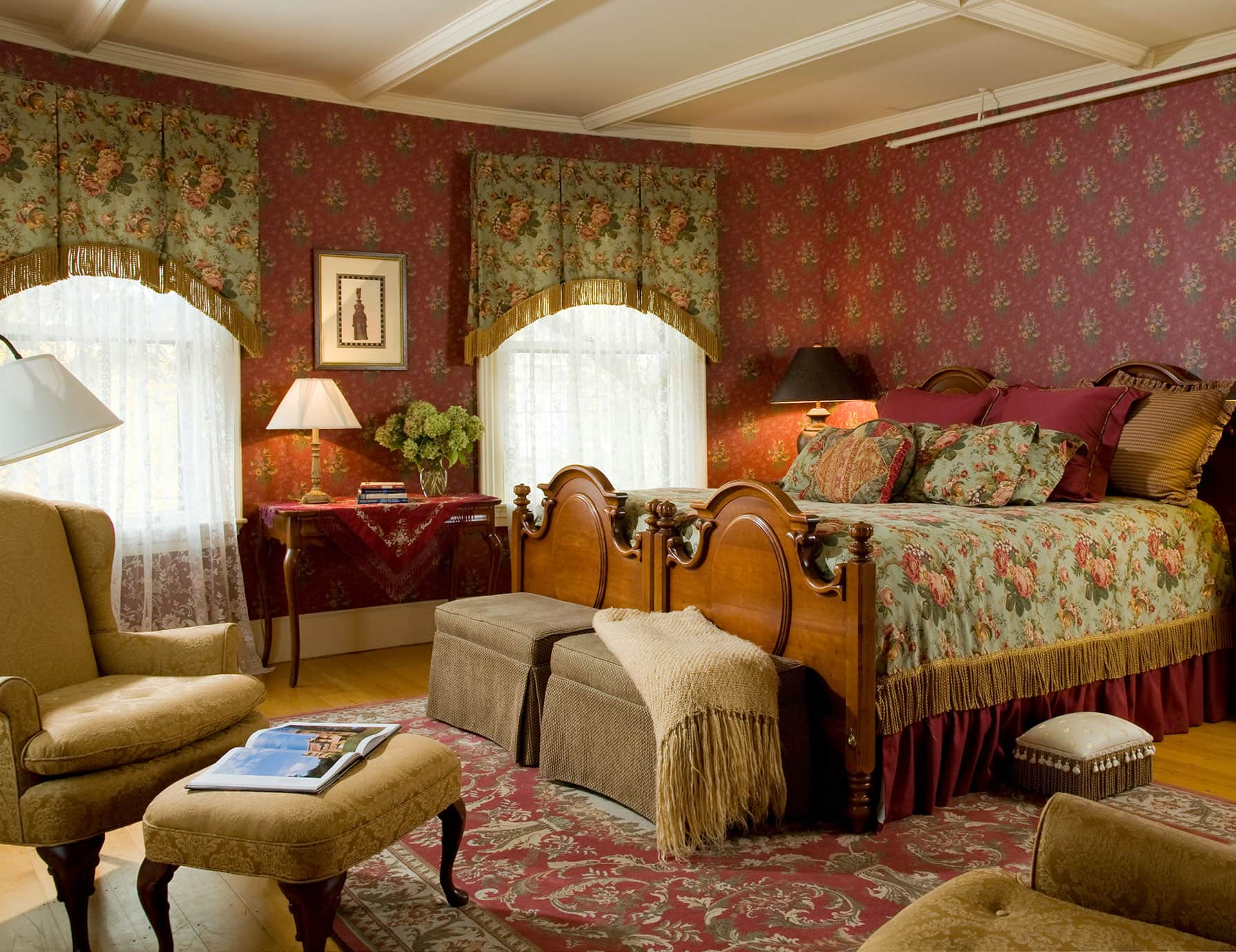 Room with ornate large bed across from sitting area and tall windows