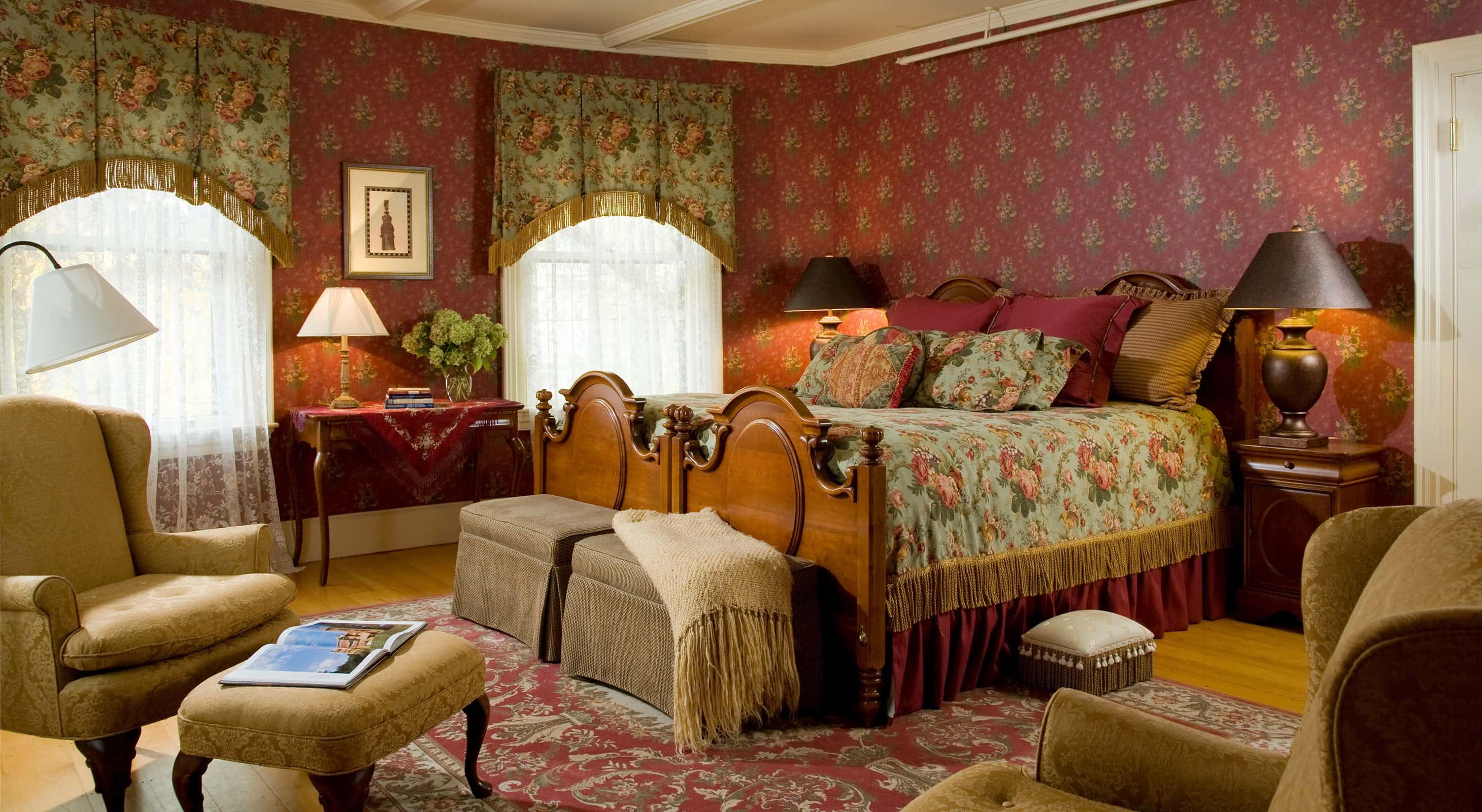 Room with ornate large bed across from sitting area and tall windows