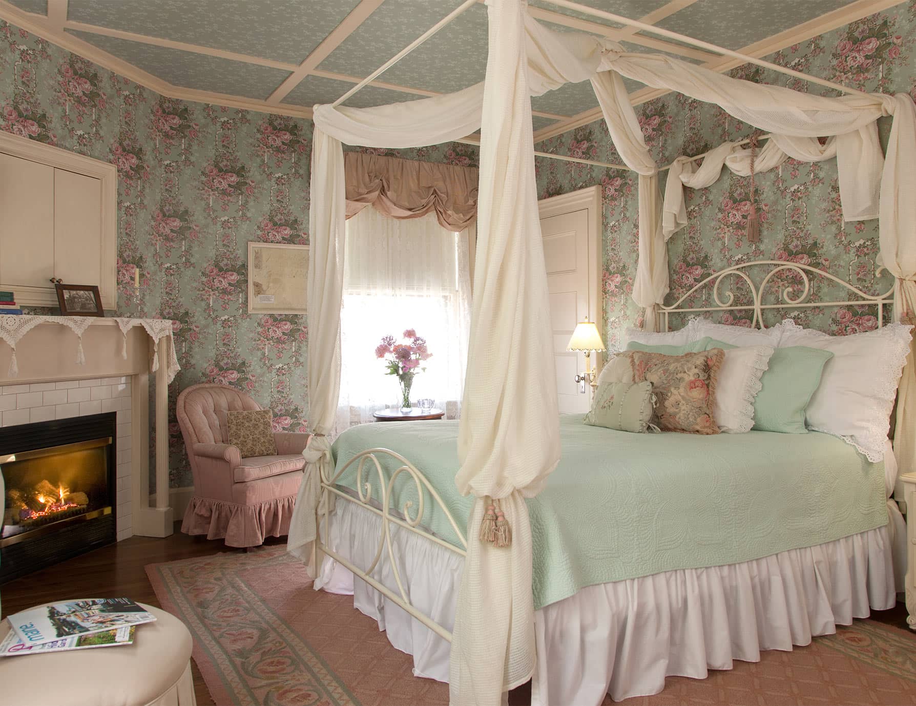 Comfortable pink bed with drapery across from fireplace in Room 4