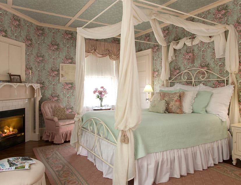 Comfortable pink bed with drapery across from fireplace in Room 4