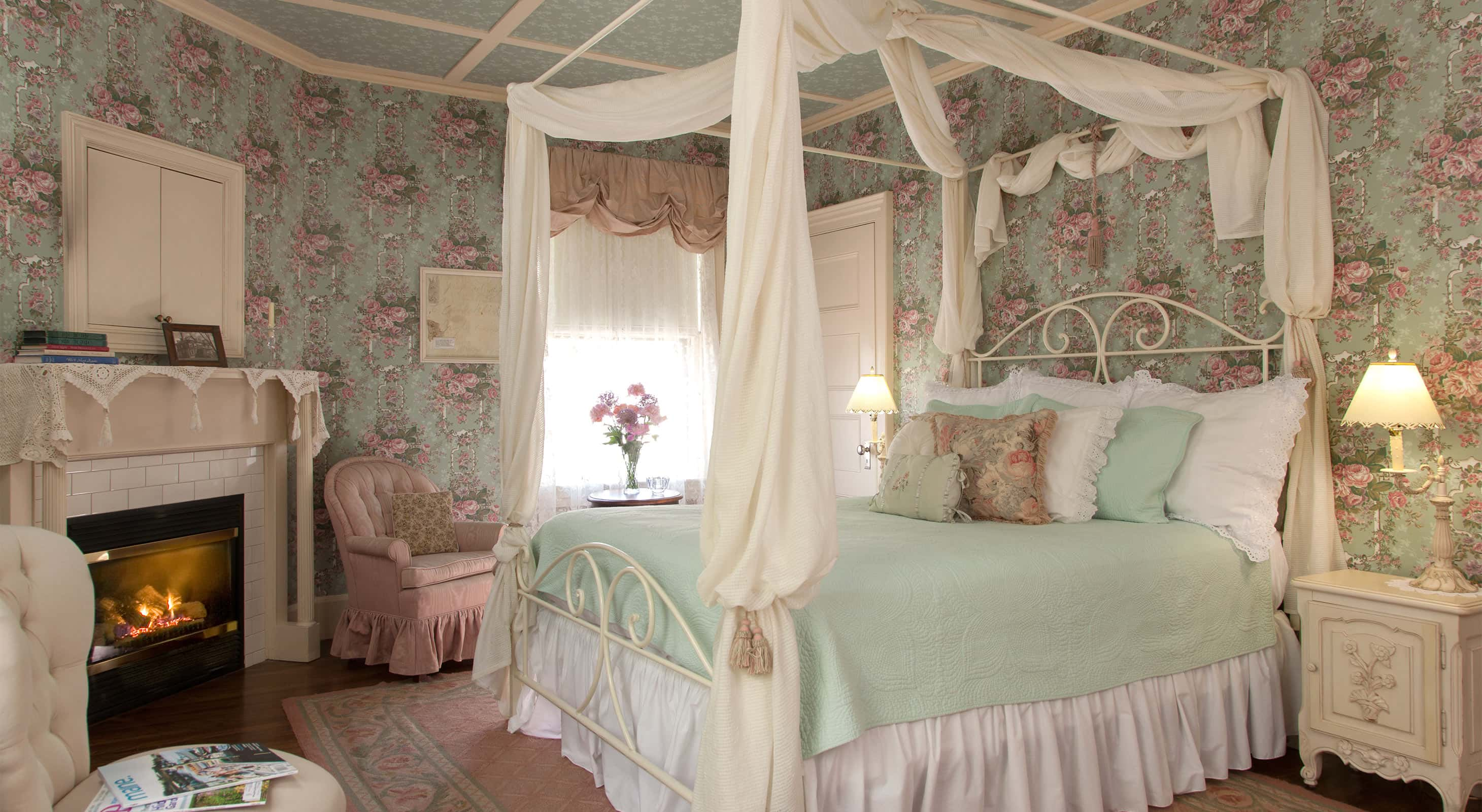 Comfortable pink bed with drapery across from fireplace in Room 4