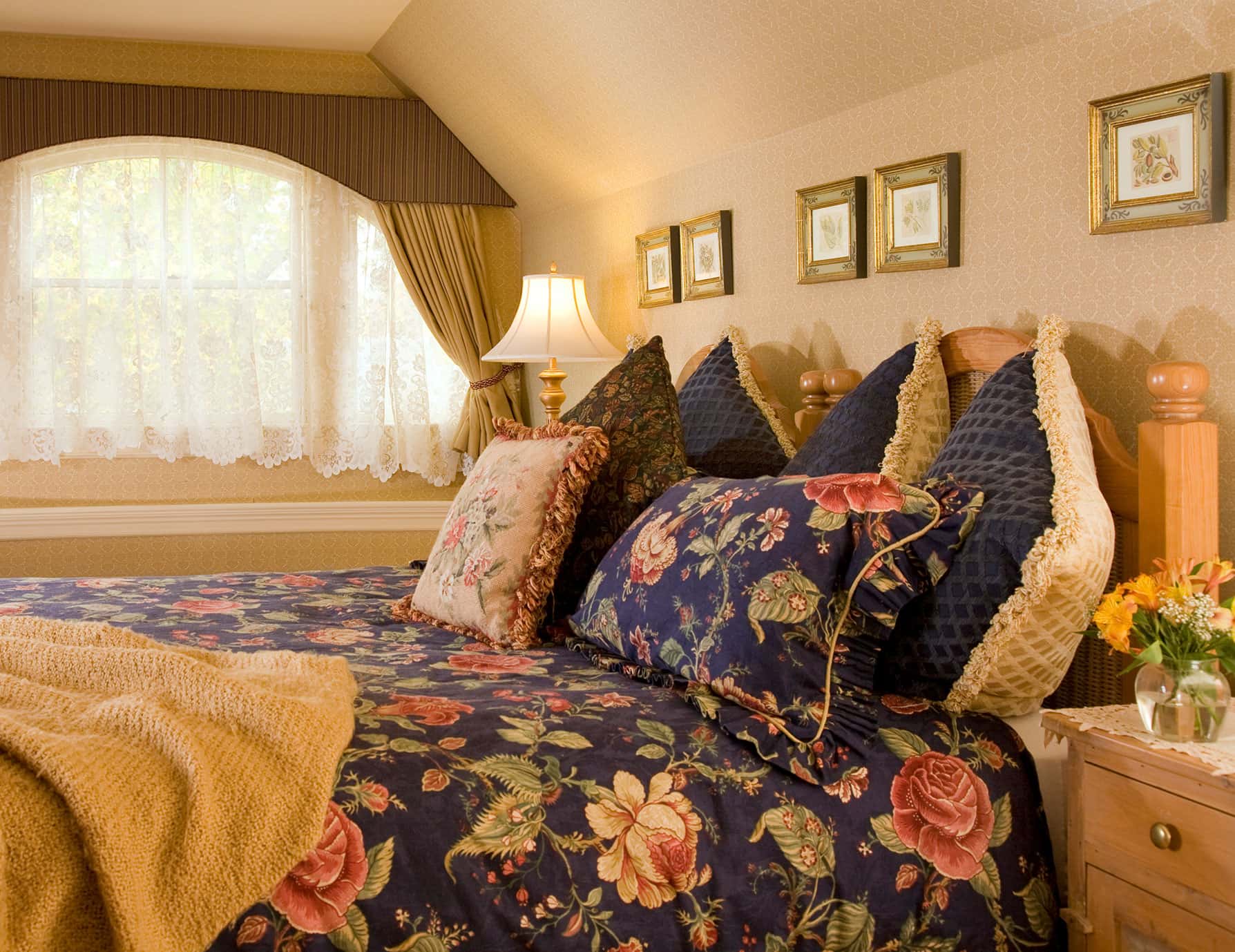 Plush bed with many pillows across from tall window in Room 5