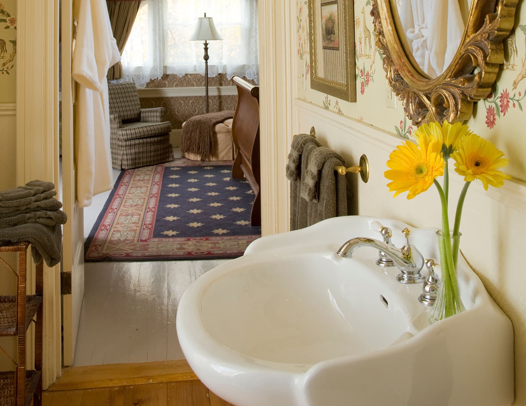 Bathroom sink and mirror with view of sitting area down the hall