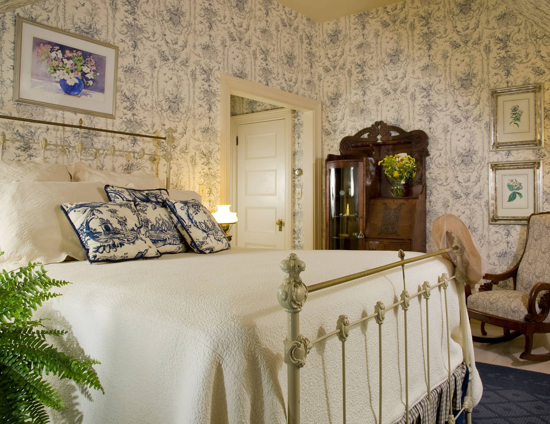 Antique-style metal bed across from ornate wooden stand in Room 7