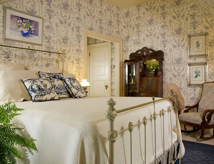 Antique-style metal bed across from ornate wooden stand in Room 7