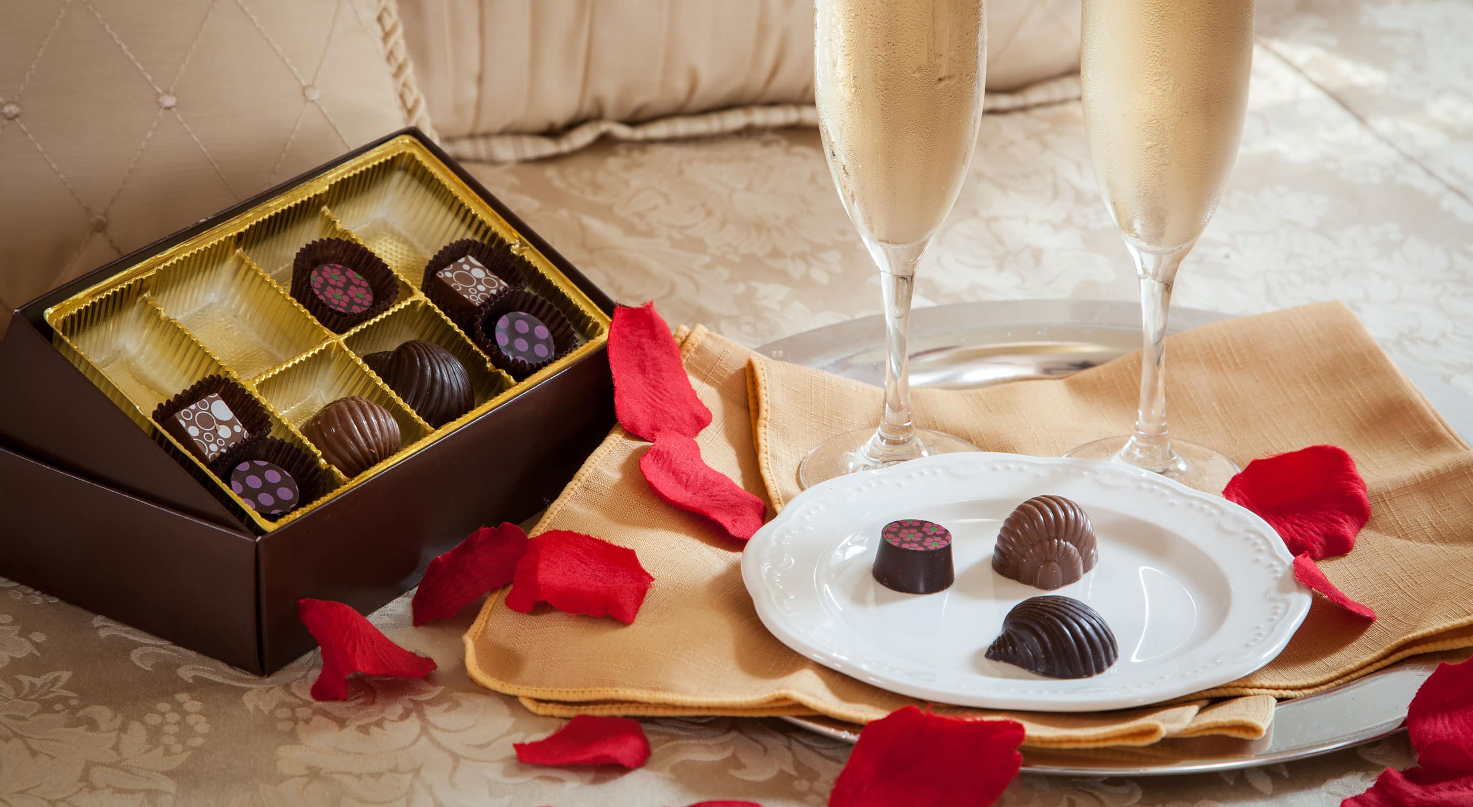 Pair of champagne glasses with plate and tray of delicious chocolates