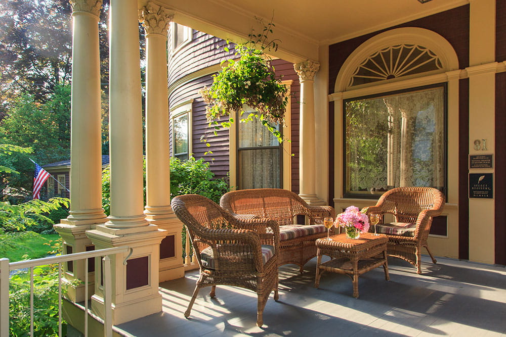 wicker seating on porch with hanging greenery