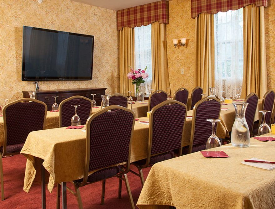 Meeting area with rows of tables and chairs in front of TV