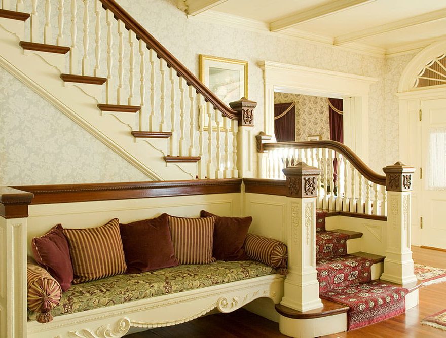 Bench sitting area with pillows under staircase