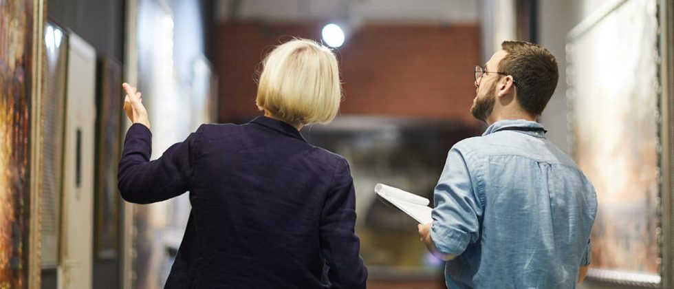 Woman showing art in a museum to a man