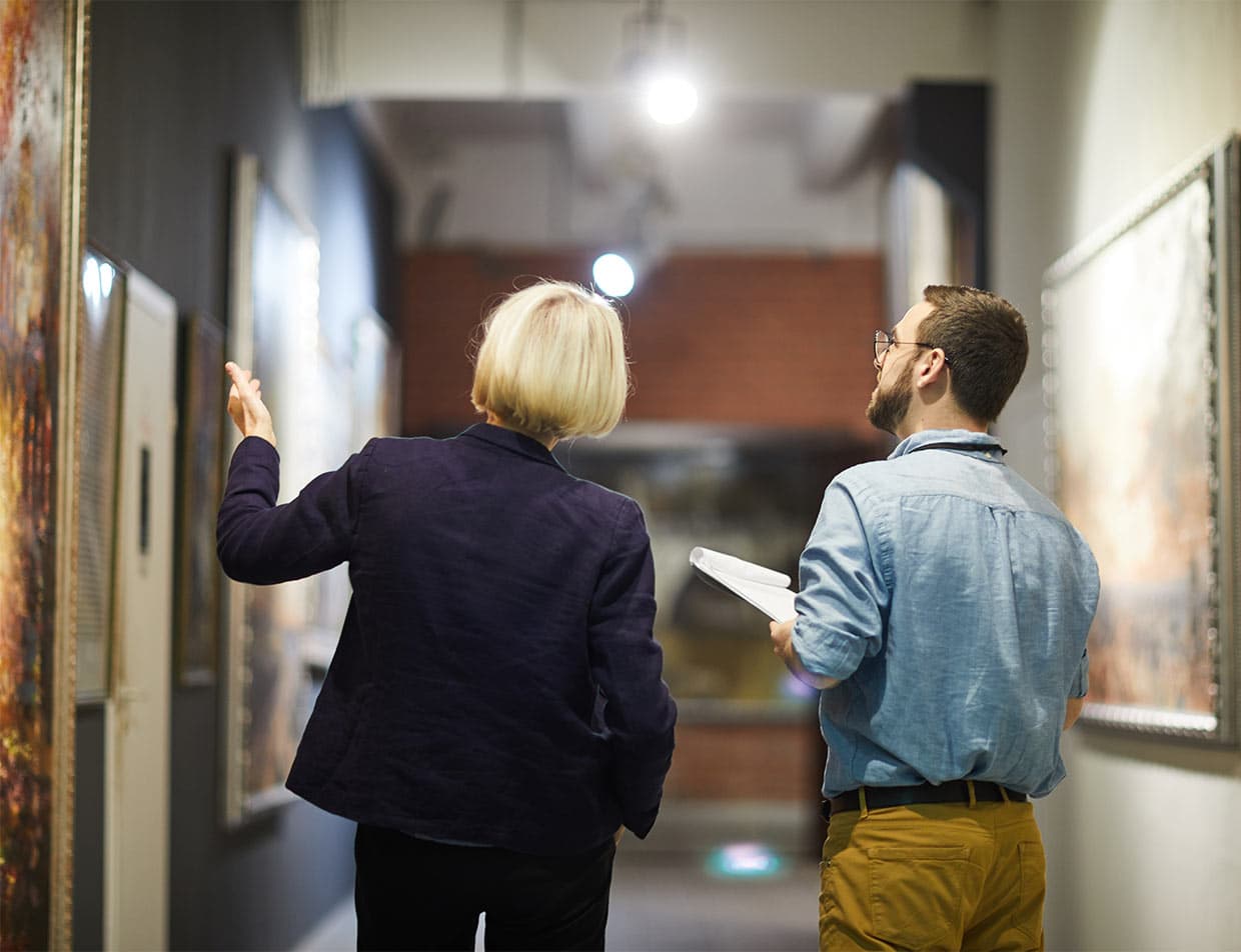 Woman showing art in a museum to a man