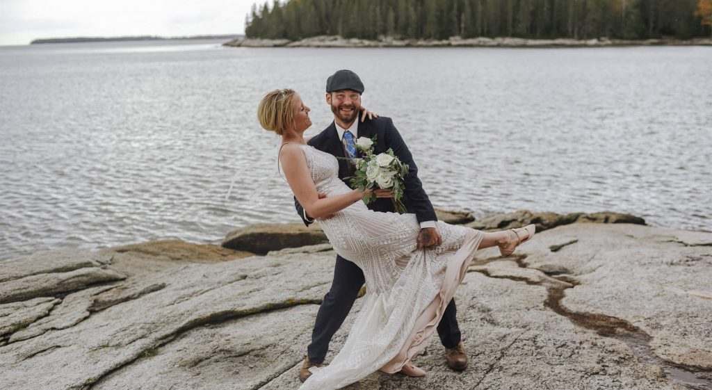 Elopement couple on rock in front of water