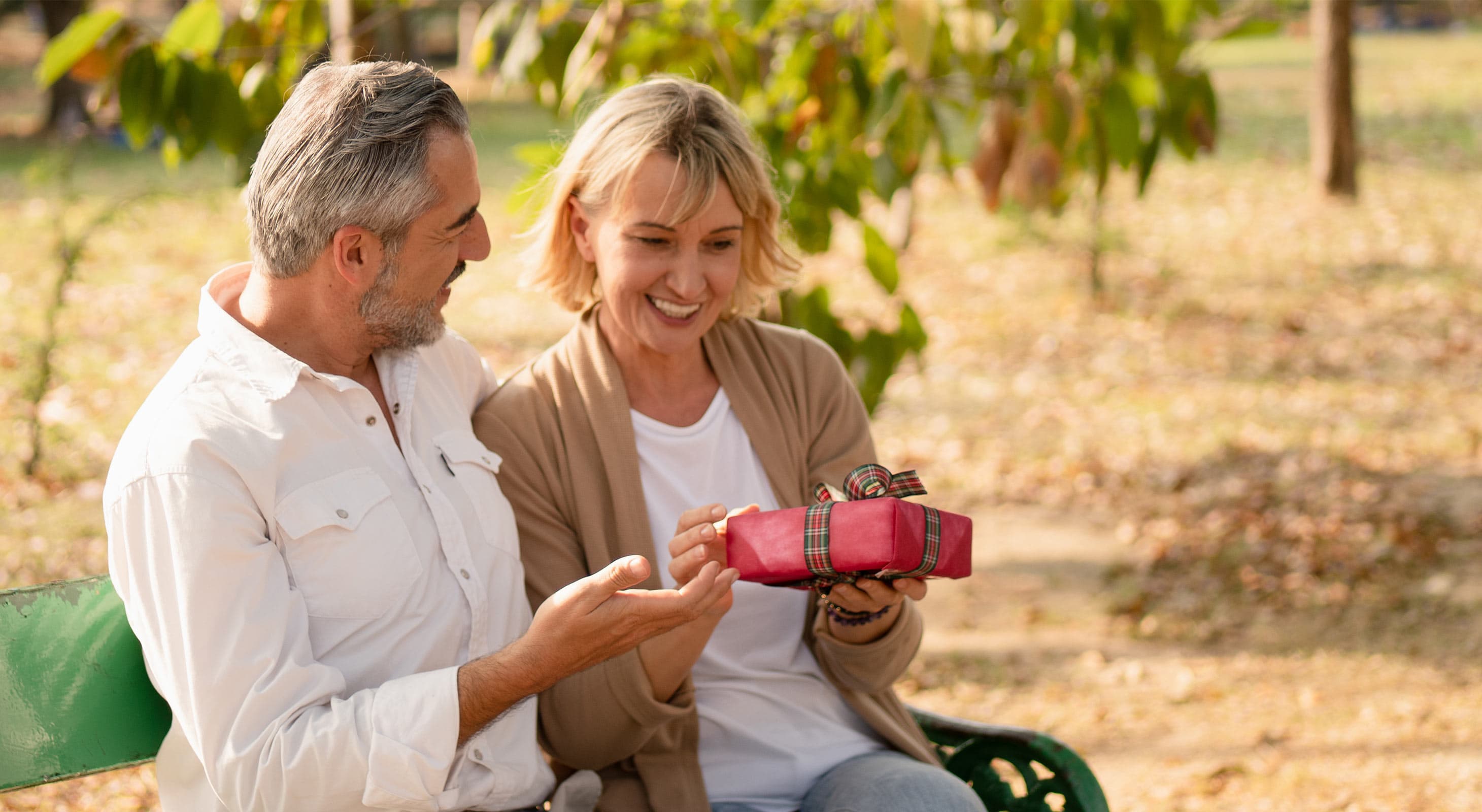 Man giving a woman a present in the park