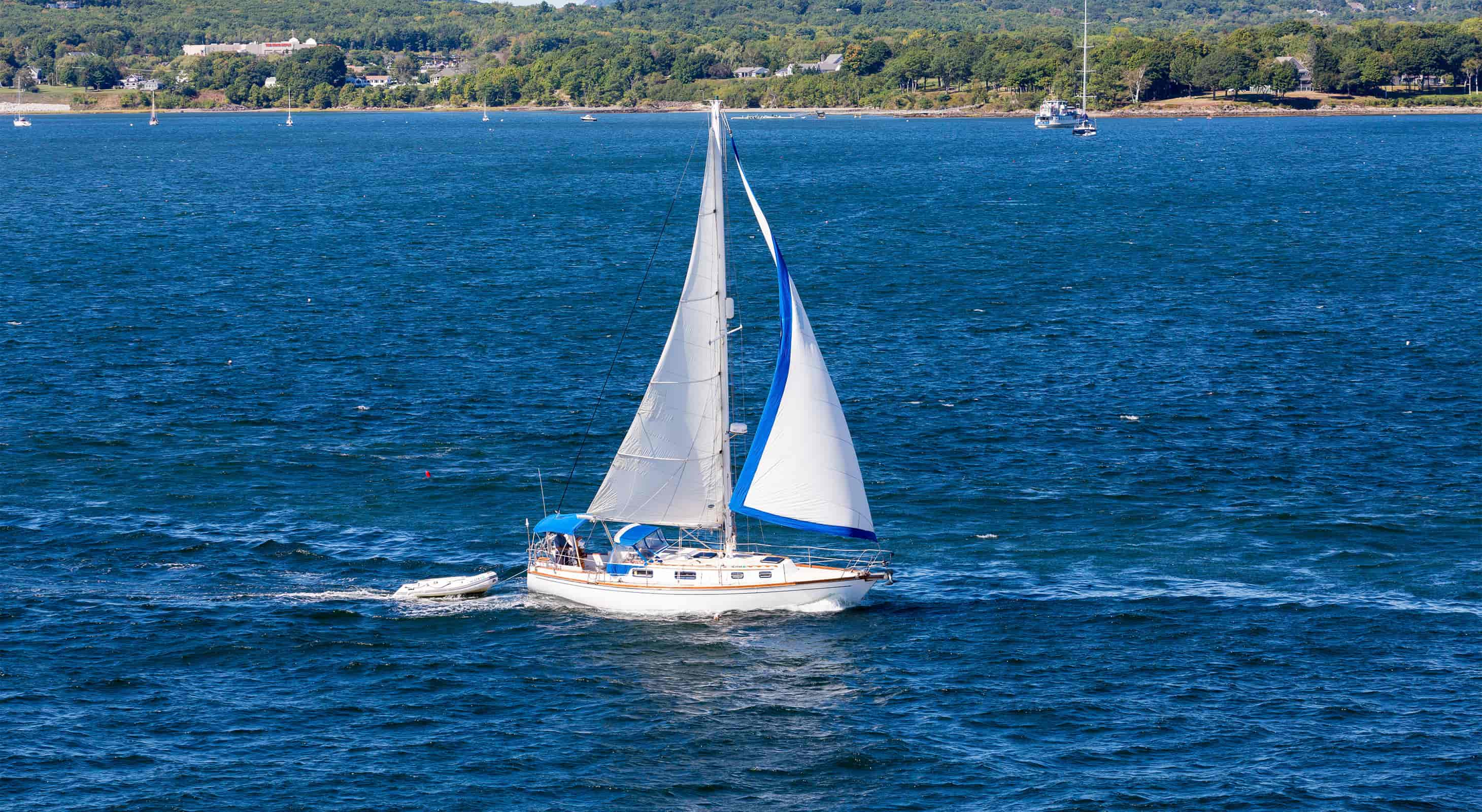 White sailboat with white sails on a blue ocean