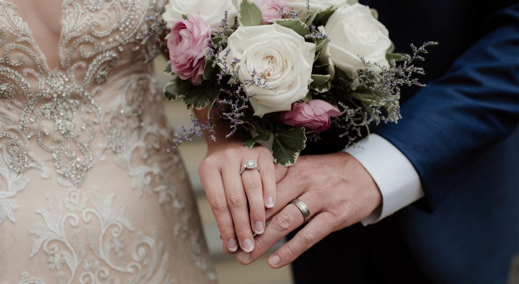 Hands of the Bride and Groom along with a flower bouquet at their petite wedding