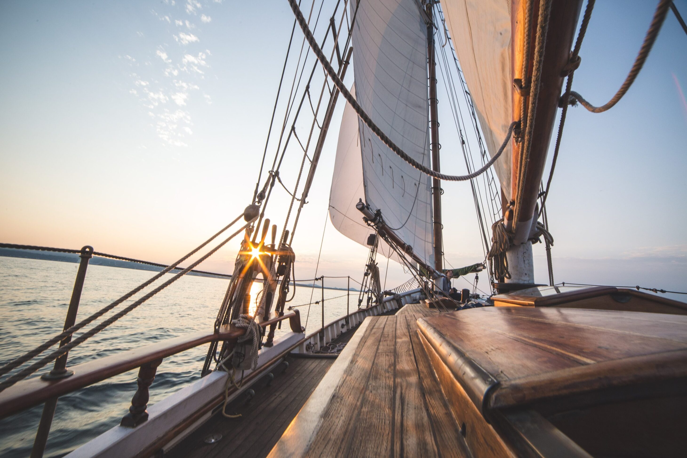 View of the sun setting over the water from a sailboat