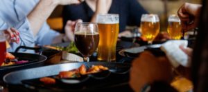 A group of friends is eating out with glasses of beer on the table