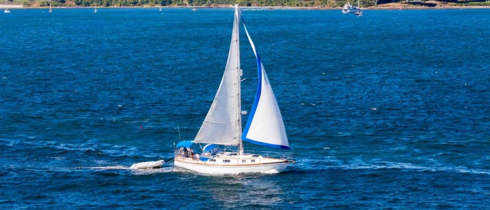 White sailboat with white sails sailing in the open blue water