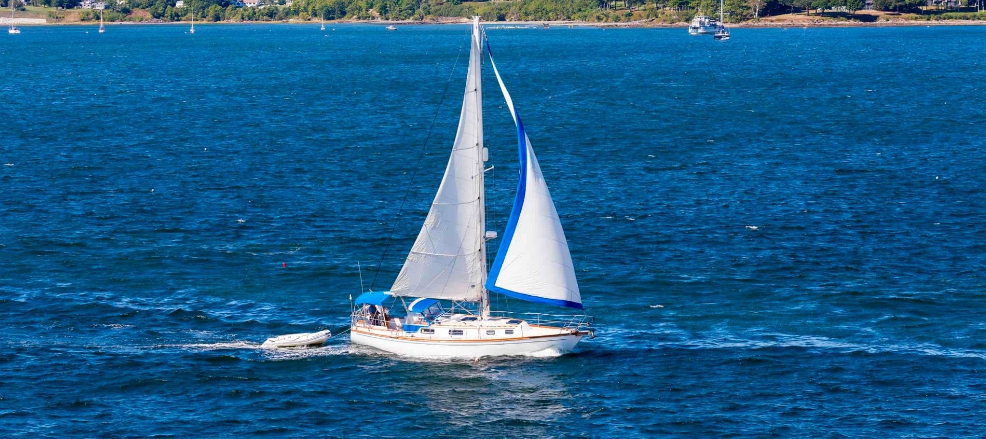 White sailboat with white sails sailing in the open blue water