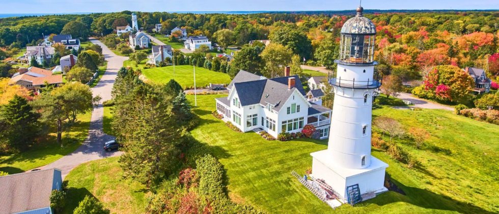 Cape Elizabeth Lighthouse with a view of the turning foliage in the background