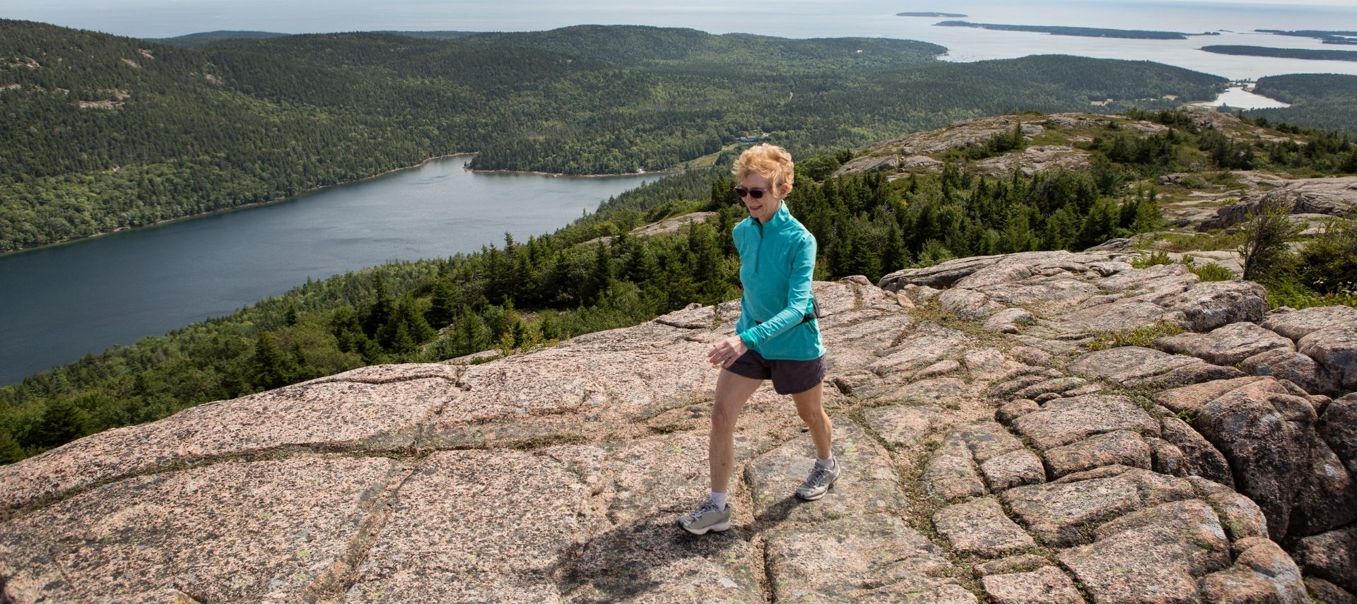 Woman hiking on the rocky Maine coastline
