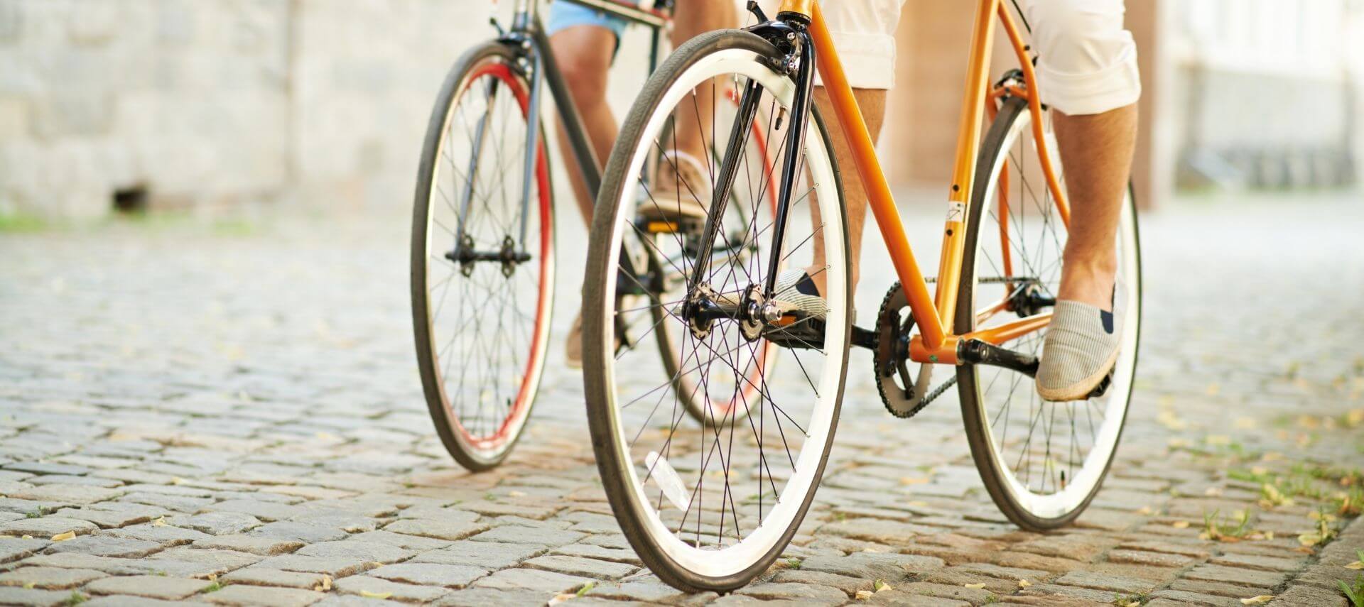 Two people riding bicycles along cobblestone road