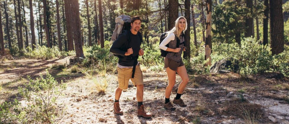 A couple is hiking with backpacks in the woods