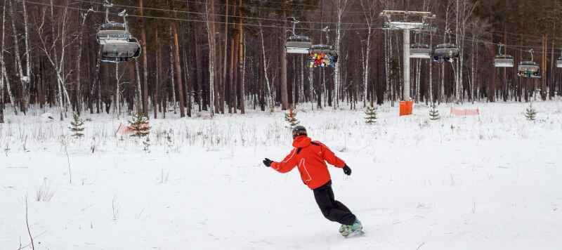 A person is snowboarding with the lift in front of them