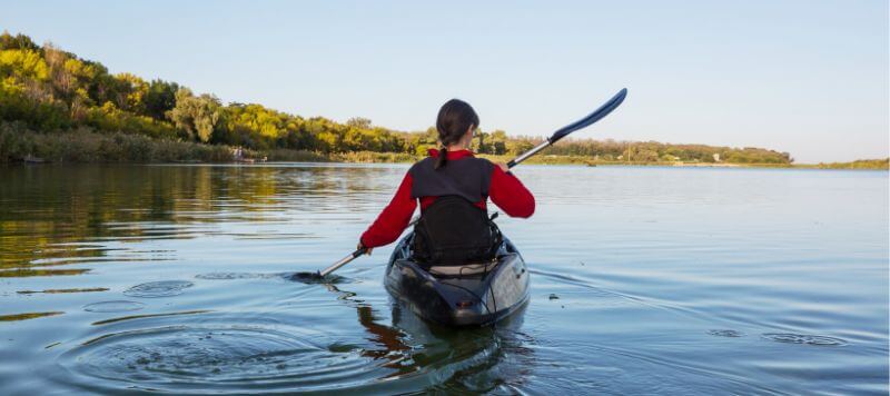 A woman is kayaking on a calm lake